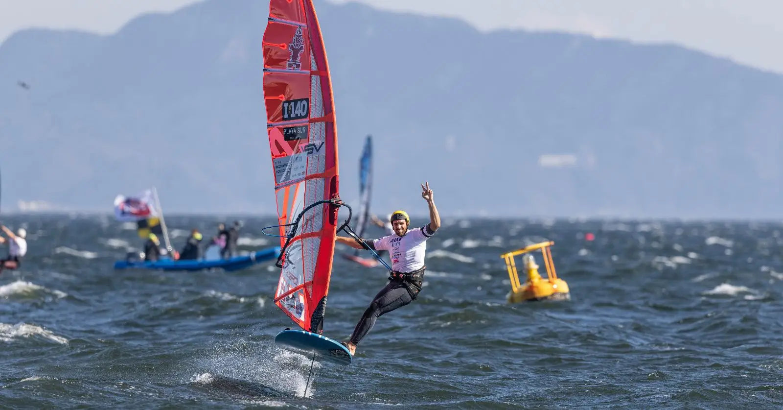 Red and white Neil Pryde windsurfing board with black fins