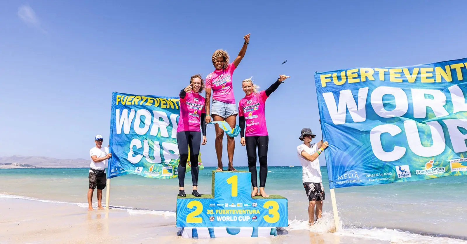 Pink surfboard with blue and white design on Fuerteventura beach