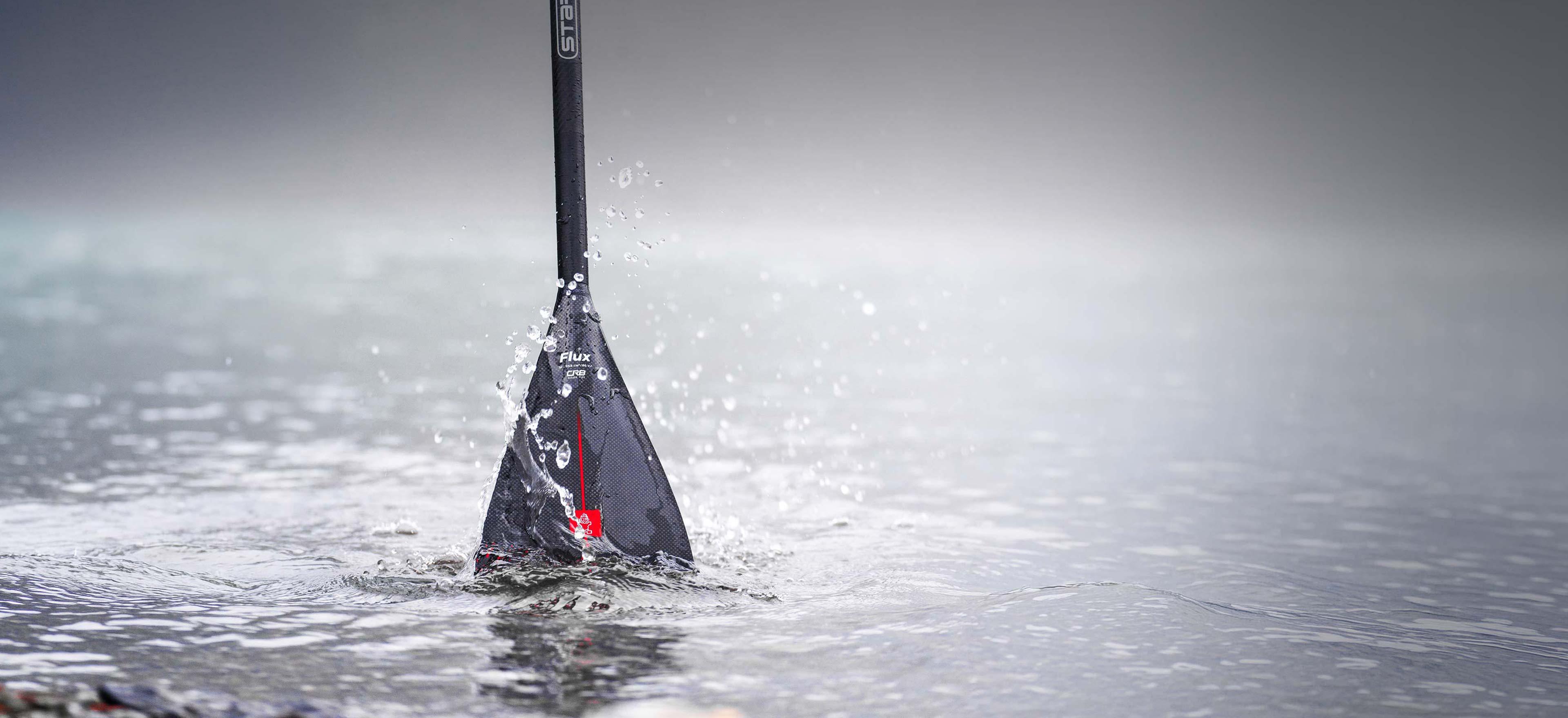 Stand-up paddleboard with black and white design in clear water, blue shorts, SUP Paddles collection