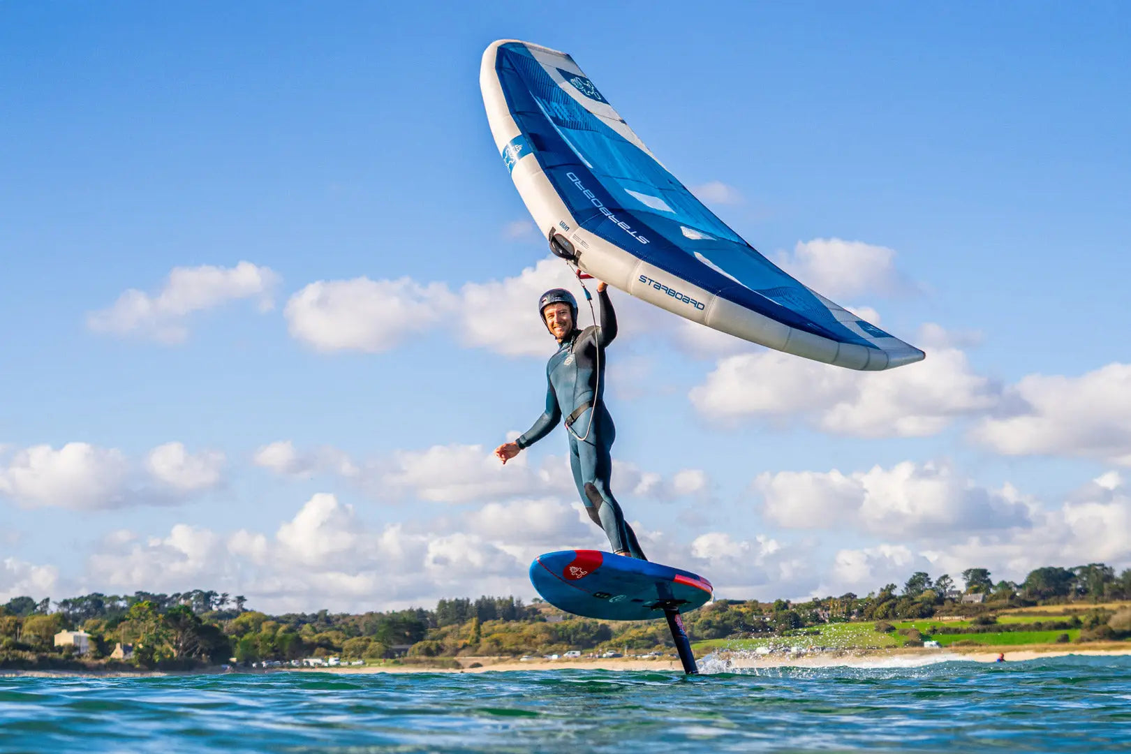 Red hydrofoil board with black fins and white sail for wing foiling